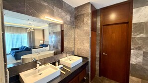Un baño moderno con dos lavamanos, un espejo grande y una puerta de madera.