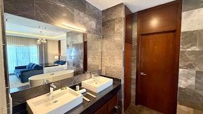 Ein modernes Badezimmer mit zwei Waschbecken, einem großen Spiegel und einer Holztür.