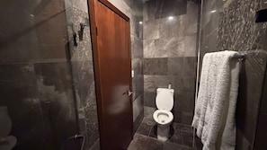 A bathroom with a toilet, a shower area, and a towel rack. - Hotel Demar Suite (Ciudad Madero)