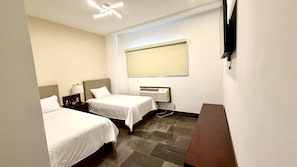 A hotel room with two beds, a desk, a telephone, and a wall-mounted TV. - Hotel Demar Suite (Ciudad Madero)