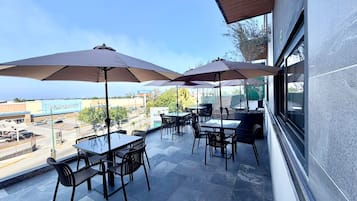 An outdoor patio with tables and chairs, umbrellas, and a view of a Walmart store.