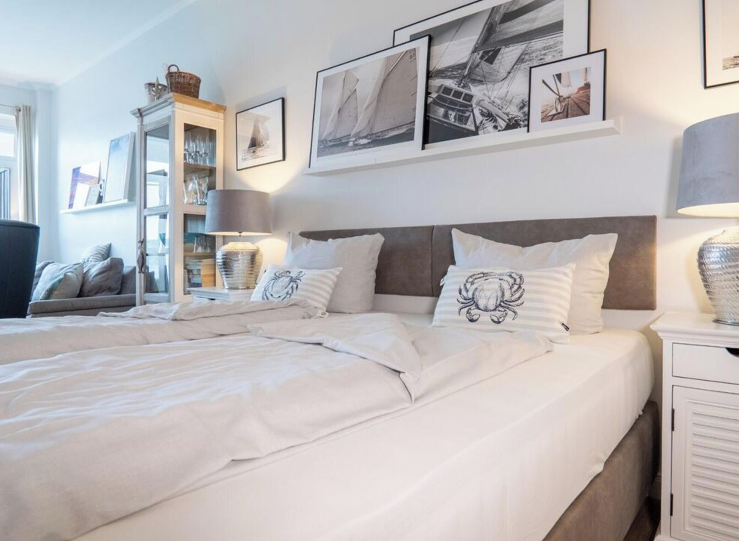 Une chambre d’hôtel avec un grand lit, deux tables de chevet, une lampe et des tableaux encadrés au mur.