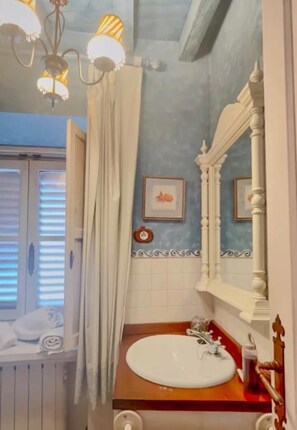 Een badkamer met een wit wastafelmeubel, een spiegel en een kroonluchter.