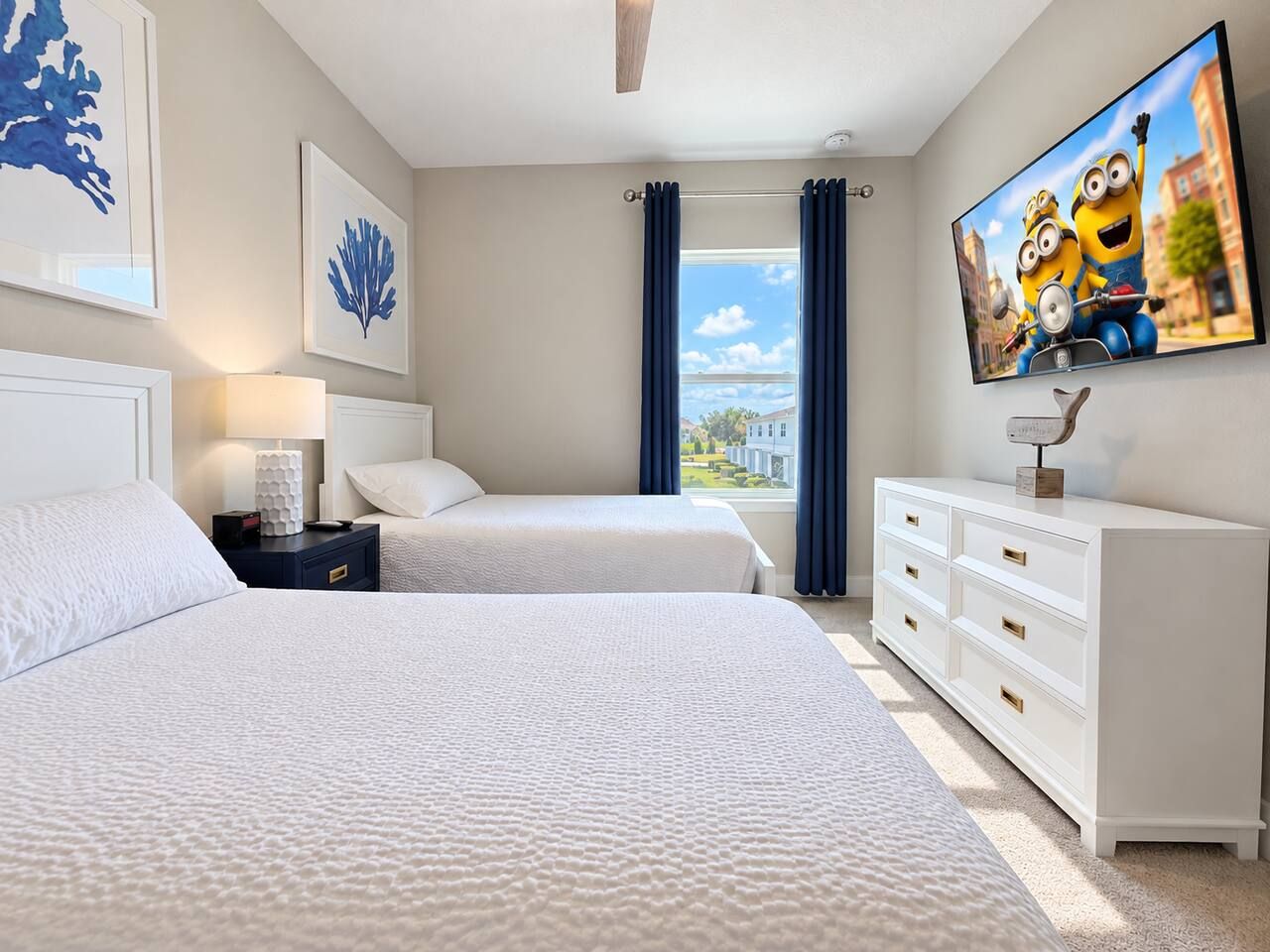 A hotel room with two beds, a TV, a dresser, and artwork on the walls.