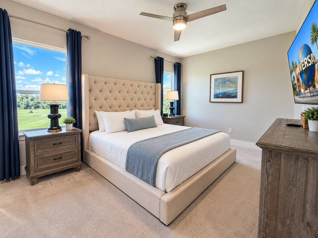 Une chambre avec un grand lit, une table de chevet, un ventilateur de plafond et une vue sur un terrain de golf.