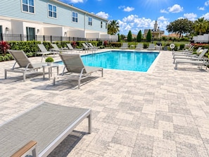 Ein Poolbereich mit Liegestühlen und einer gefliesten Terrasse.