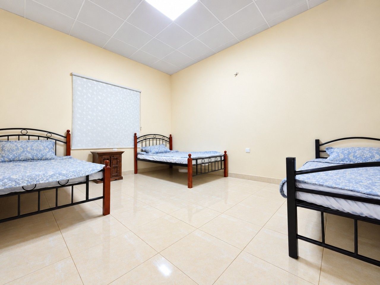 A room with three beds, a whiteboard, and a cabinet.