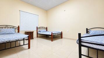 A room with three beds, a whiteboard, and a cabinet.