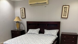 Un dormitorio con una cama grande, una mesita de noche, una lámpara y un aparador.