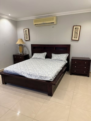 Quarto com uma cama grande, mesa de cabeceira, abajur e cômoda.