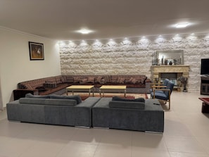 Uma sala de estar com sofá seccional, mesa de jantar e lareira.