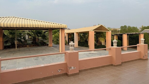 Una terraza en la azotea con zona de estar cubierta y barandilla decorativa.