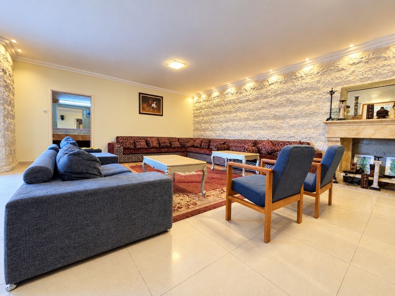 A modern living room with a sectional sofa, a coffee table, and a fireplace.