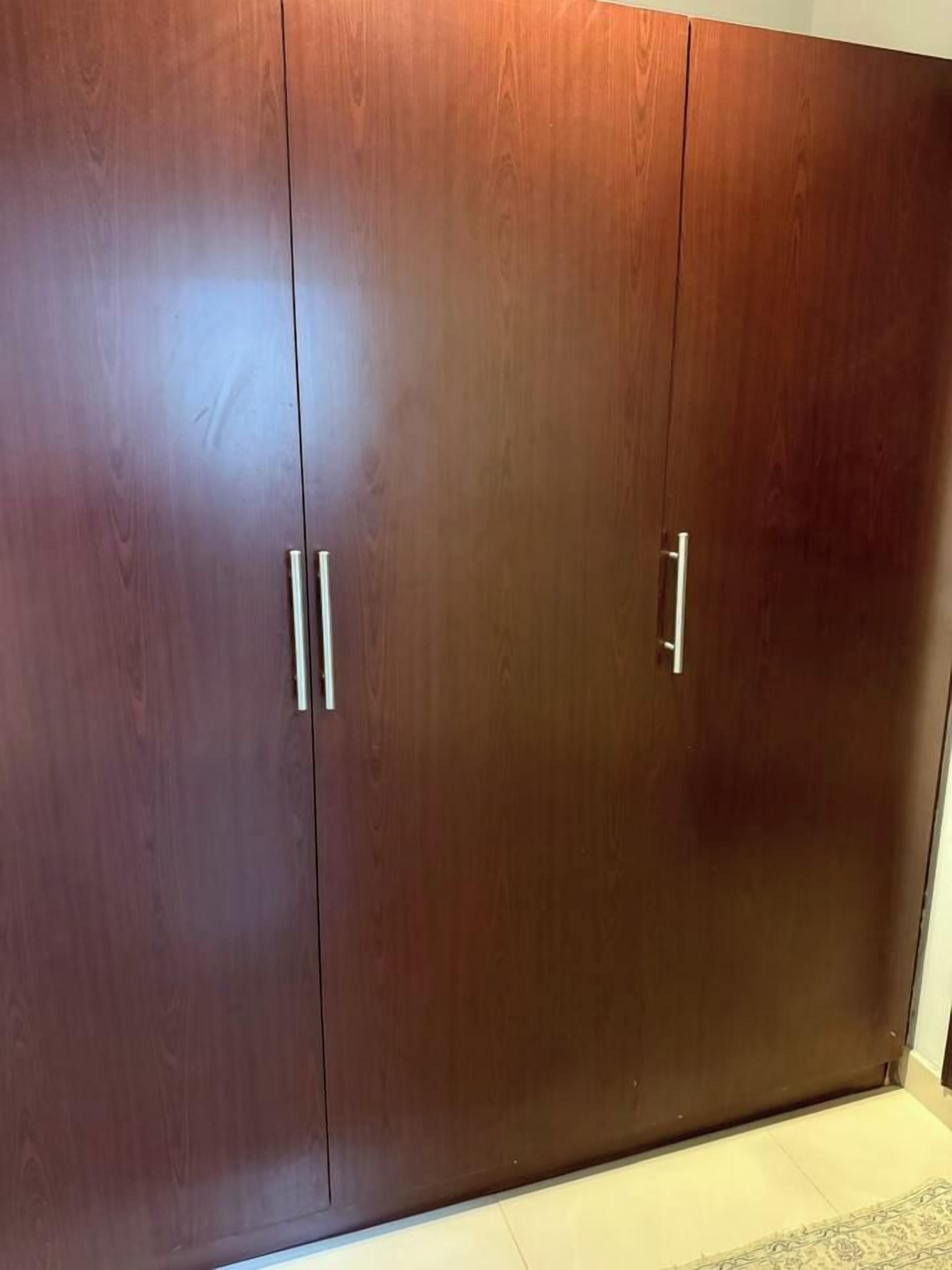 A large wooden wardrobe with two doors and a handle on each door.