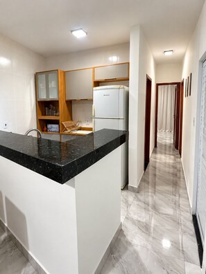 A modern kitchen with a marble countertop, built-in cabinetry, and a refrigerator. - Cinema & Beach Experience • Exclusive Couple's Home (Rio das Ostras)
