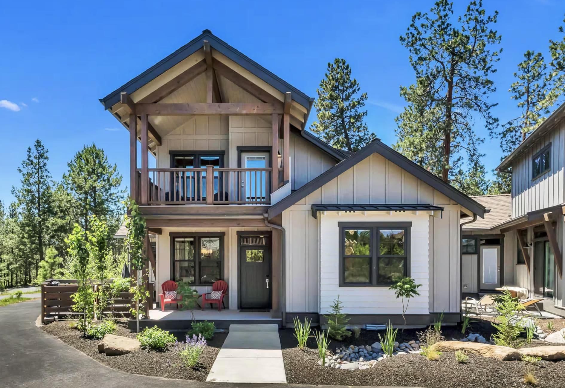 A two-story house with a balcony, a front porch with chairs, and a small attached garage.