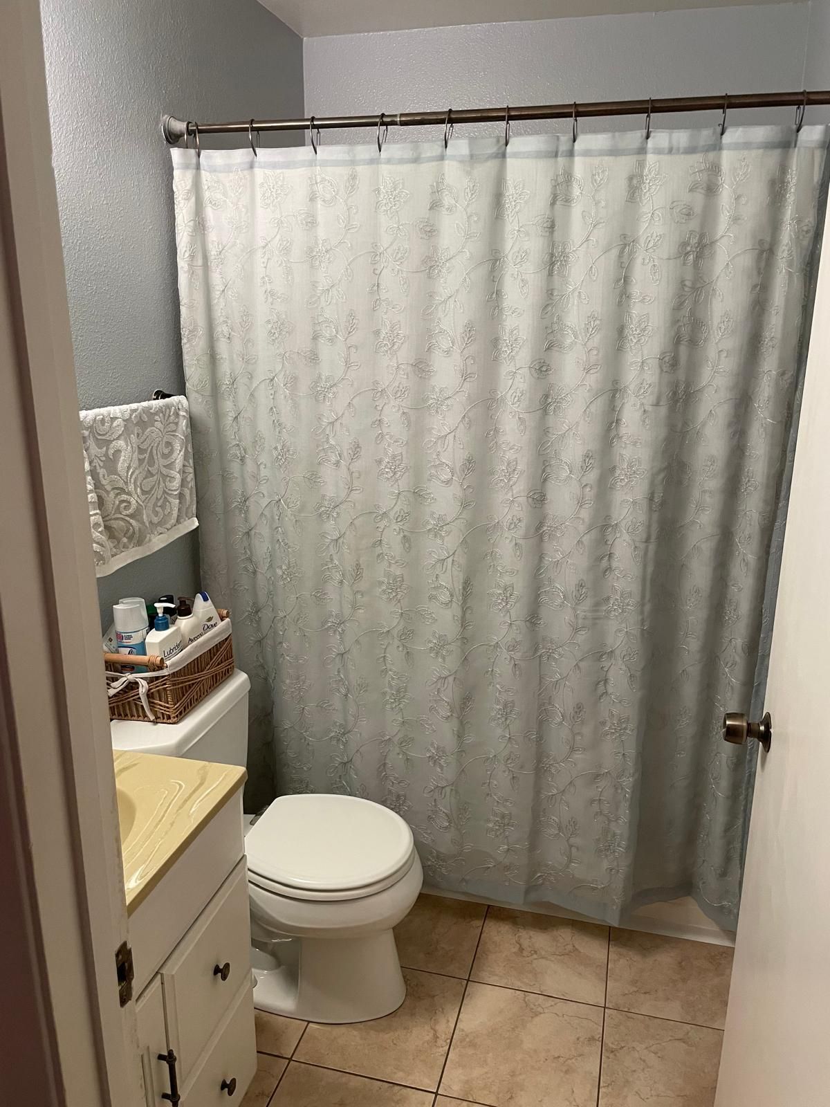 Et badeværelse med toilet, brusekabine og et skab med toiletartikler.