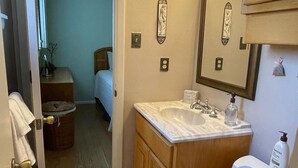 Een badkamer met een wit toilet, een wastafel met een marmeren aanrechtblad, houten kastjes en een spiegel met een decoratieve lijst.