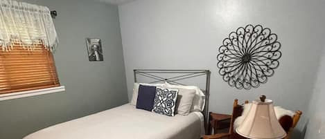 Un dormitorio con cama, una silla, una lámpara y un adorno en la pared.