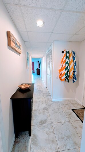 A hallway with a wooden sign, a black table with a woven basket, and striped towels on the wall. - 2nd floor Serene Views updated Villa sleeps 8 (Panama City Beach)