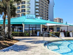 Un bar-restaurant appelé « Oceans », avec un toit turquoise, situé à côté d’une piscine.