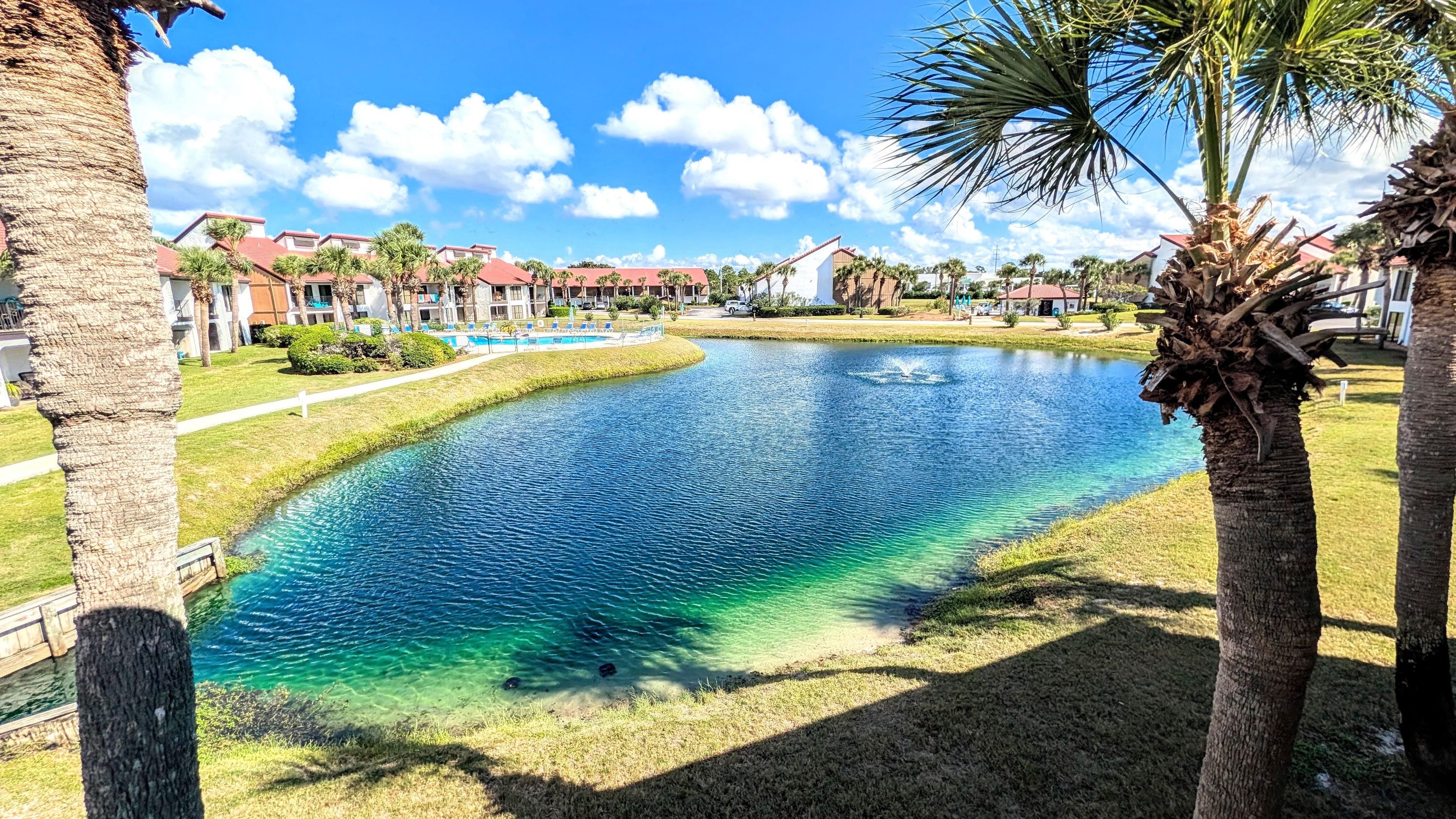 View from balcony overlooking pond with fountain and lakefront pool