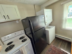 A compact kitchen with a stove, refrigerator, and washing machine. - UrbanCottage | 1mi Mayo Clinic, No Stairs, Dogs OK (Rochester)