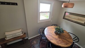 A dining area with a wooden table, black chairs, a bench, a hanging light fixture, a window, and a framed picture on the wall. - UrbanCottage | 1mi Mayo Clinic, No Stairs, Dogs OK (Rochester)