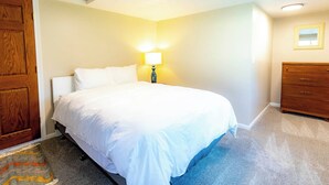 A bedroom with a bed, a dresser, a lamp, and a door. - UrbanCottage | 1mi Mayo Clinic, No Stairs, Dogs OK (Rochester)