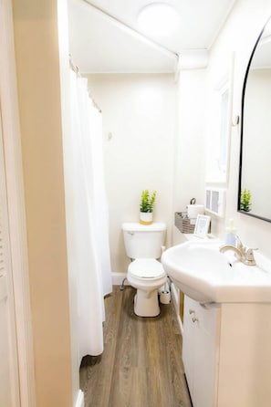 Une petite salle de bain comprenant des toilettes, un lavabo et un rideau de douche.