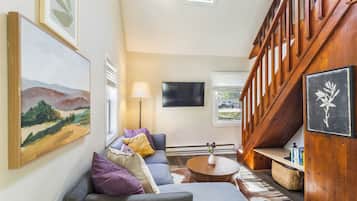 A living room with a sofa, a coffee table, and a painting on the wall.