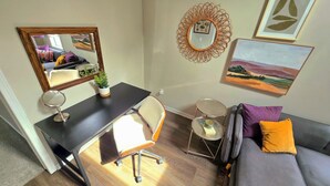 A furnished room with a desk, chair, mirror, small round table, and a sofa. - UrbanCottage | 1mi Mayo Clinic, No Stairs, Dogs OK (Rochester)