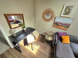 Une chambre meublée comprenant un bureau, une chaise, un miroir, une petite table ronde et un canapé.