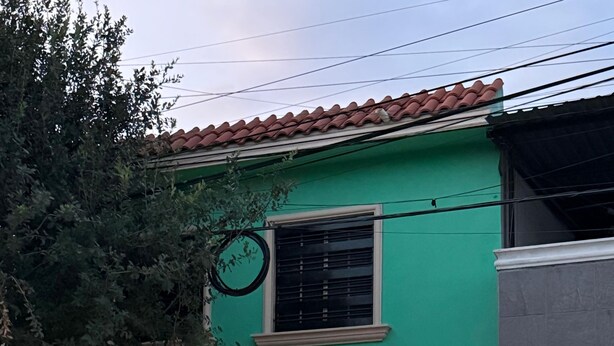 Ein Wohngebäude mit grüner Fassade, einem Ziegeldach und einer Garage mit beleuchtetem Rolltor.