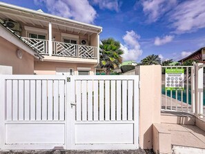 Entrada fechada por portão para uma propriedade com área de piscina, varanda e placa com as regras da piscina.