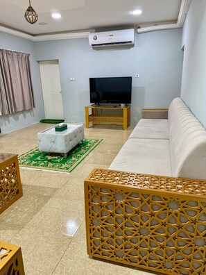 A living room with a sofa, a television, and a decorative partition.