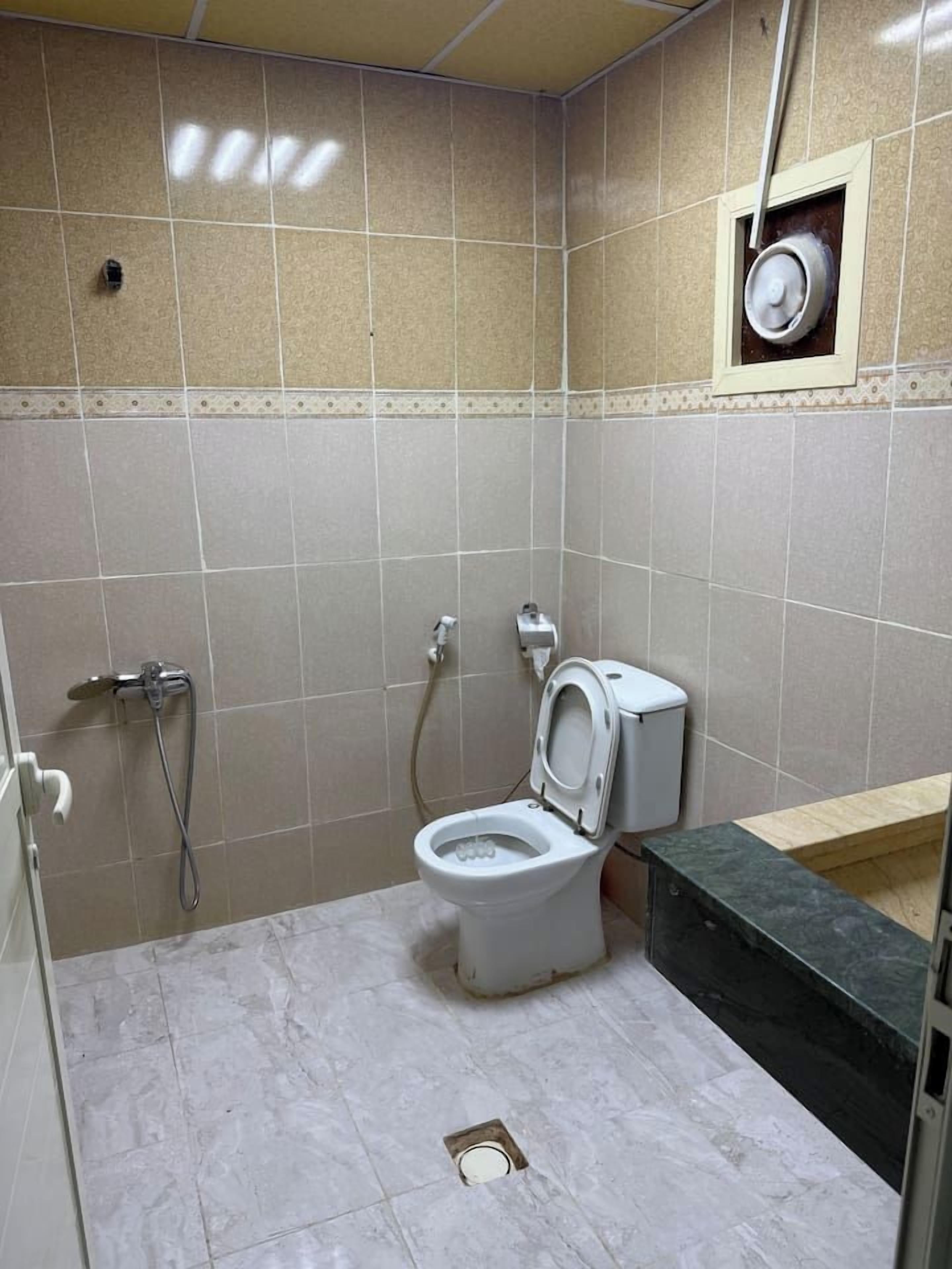 A bathroom with a toilet, shower, and sink.