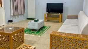 Een woonkamer met een flatscreen televisie, een bank, een salontafel en decoratieve houten schermen.