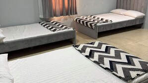 Een kamer met twee eenpersoonsbedden, een raam met gordijnen en een luchtbevochtiger aan de muur.