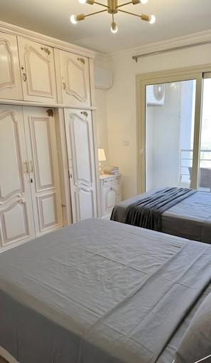 Ein Schlafzimmer mit zwei Betten, einem Schminktisch, einem Spiegel und einem Fenster.