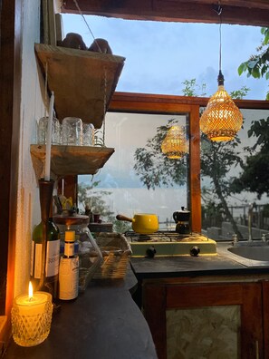 Cozinha com fogão, luminárias pendentes e janela com vista para a rua.