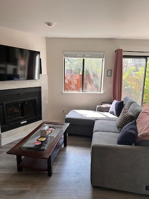 Ein Wohnzimmer mit Kamin, einer Couch, einem Couchtisch und einem Fernseher.