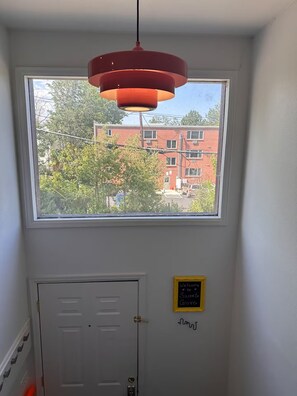 Une pièce avec une fenêtre, une porte et un luminaire suspendu.