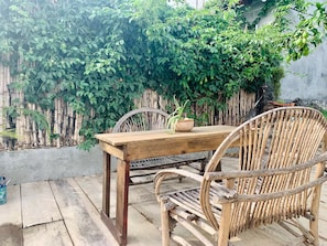 A rustic outdoor dining area with a wooden table and chairs, surrounded by lush greenery and a bamboo fence. - Our Birdhouse - Relax & Swim - Your Peaceful Getaway (San Pedro La Laguna)