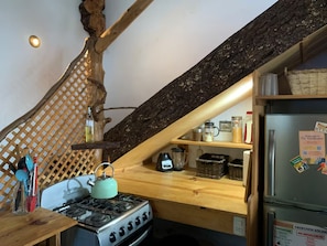 A kitchen with a gas stove, wooden shelves, and a refrigerator with magnets. - Our Birdhouse - Relax & Swim - Your Peaceful Getaway (San Pedro La Laguna)