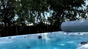 A hot tub with a wooden deck and a wooden fence in the background. - Pet Friendly Trophy Club 3BR Retreat, Swim Spa, Huge Patio. Office, Near Schwab (Trophy Club)