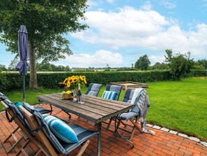 An outdoor patio with a wooden table, chairs, and a sun umbrella. - Holiday Apartment With 1 Bedroom (Steinberg)