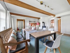 Ein modernes Wohnzimmer mit einer hölzernen Bank, einem Esstisch und einem weißen Stuhl.