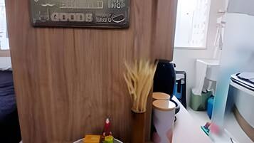 A wooden wall with a framed map and a small table with a mouse, a candle, and a cup.