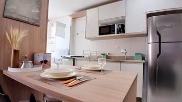 Una cocina moderna con armarios blancos, un refrigerador de acero inoxidable y una isla de madera con platos y cubiertos.